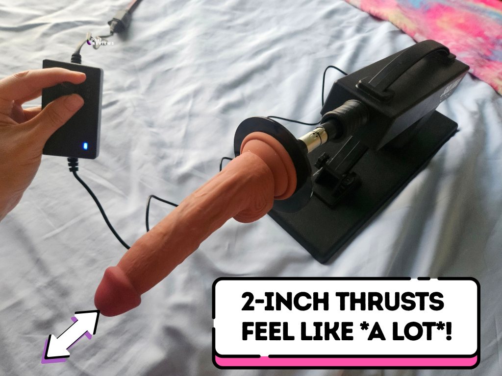 Arrows indicate distance covered by brown realistic thrusting dildo mounted on Strong Small thrusting sex toy, with overlaid bubble reading "2-Inch thrusts feel like *a lot*!"