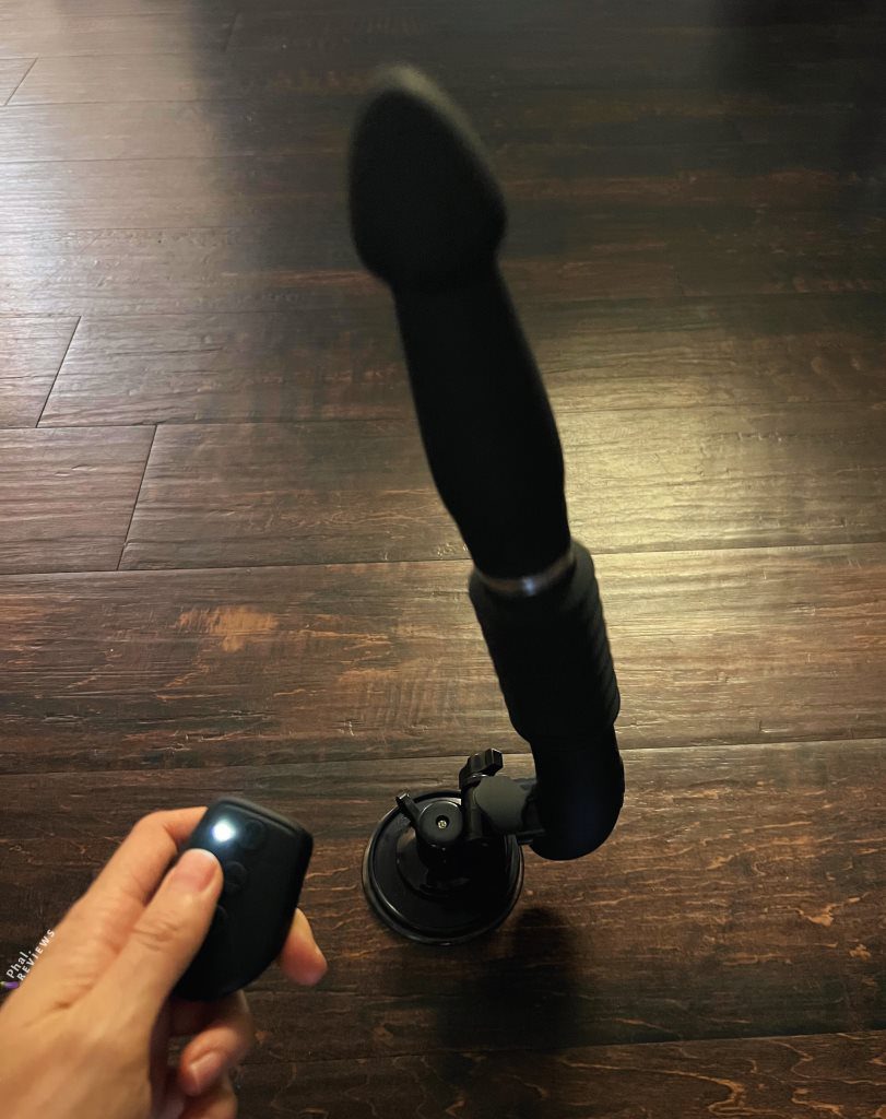 RC Fucking Machine thrusting dildo with suction cup and remote in hand