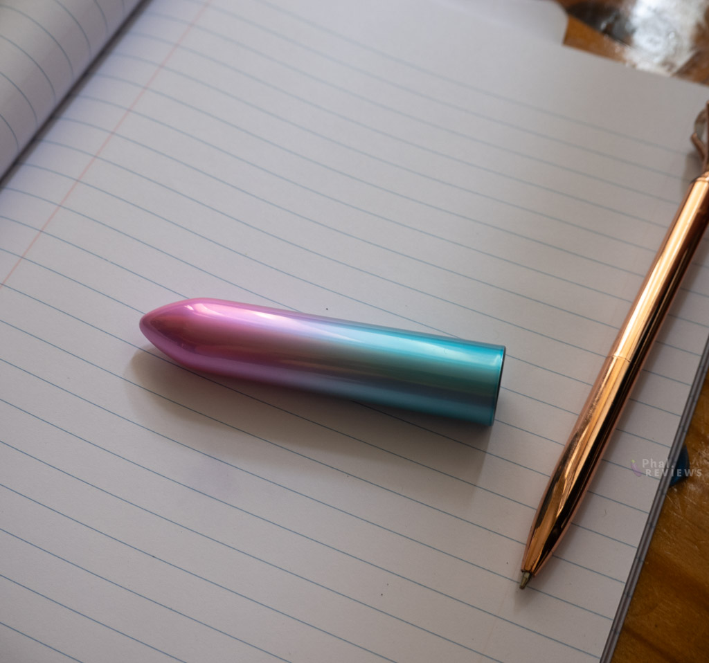 Shimmr bullet vibrator's rounded tip vs. full length over white notebook paper with gold pen to right side to show sizing