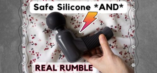 Black and gray Super Power Massage gun being reached for by hand, in front of floral red, pink, black background. Overlaid text reads "Safe silicone *and* real rumble"
