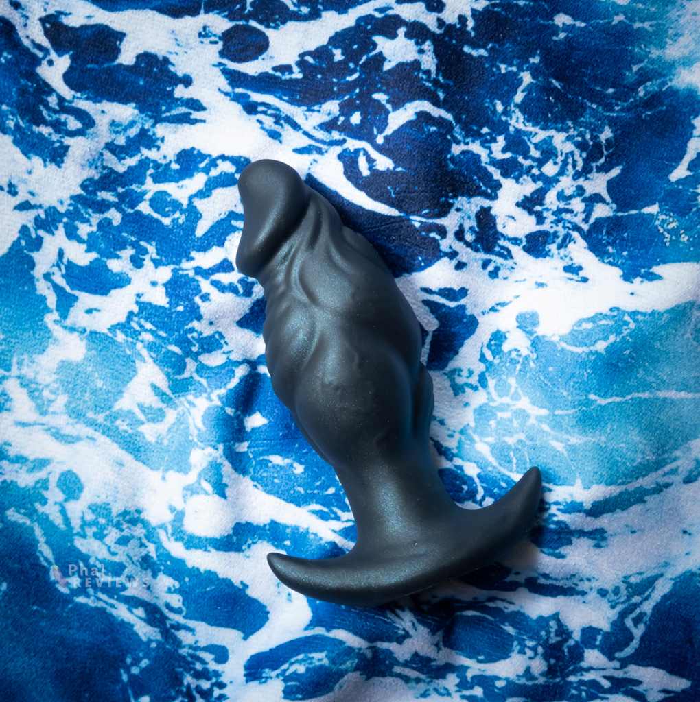 Thane large plug's dark-blue-black color over wave print fabric background