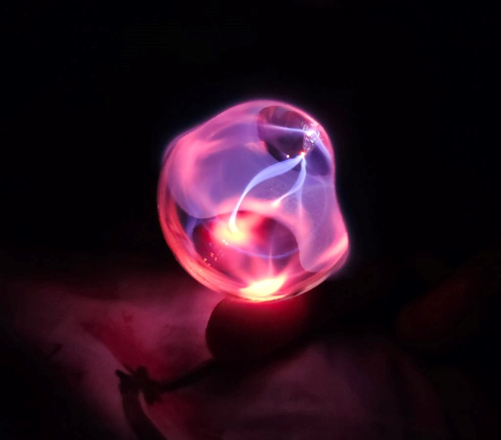 The Orb vibrator glowing sex toy on fingers in dark plasma rays 1