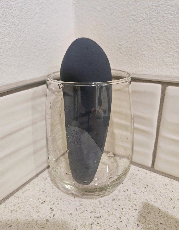 Womanizer Vibe's beak protrudes over drinking glass edge